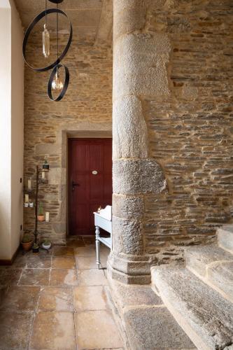 a stone building with a red door and a stone wall at La Metairie-du-Vauhariot - Vue Mer et Mont Saint Michel - Piscine Chauffée - Accès GR34 in Cancale