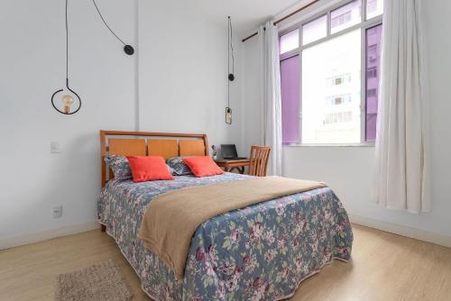 Un dormitorio con una cama con almohadas rojas y una ventana en PERFEITO 2 Quartos a pé Praia de Copacabana, wifi, ar, lavanderia e cozinha completa, en Río de Janeiro