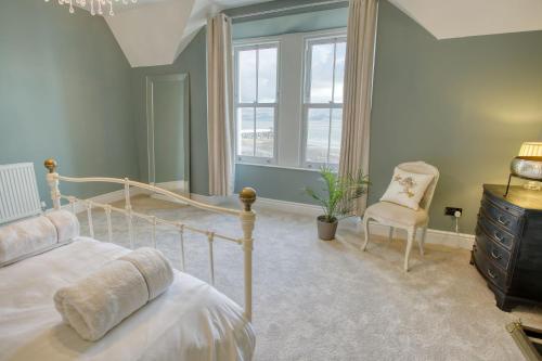 a bedroom with a bed and a chair and a window at Craig Hyfryd in Beaumaris
