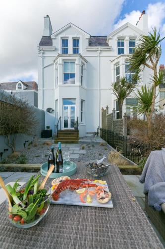 a table with a plate of food and a house at Craig Hyfryd in Beaumaris