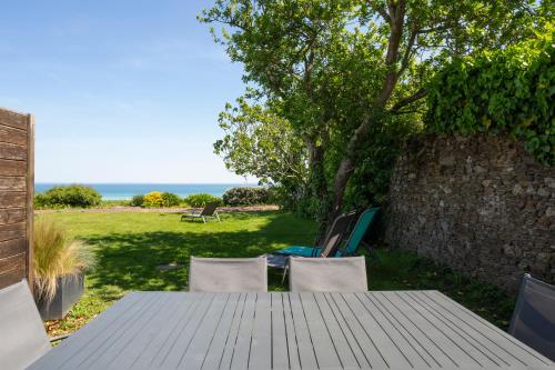 a wooden table and chairs with a view of the ocean at La Metairie-du-Vauhariot - Vue Mer et Mont Saint Michel - Piscine Chauffée - Accès GR34 in Cancale