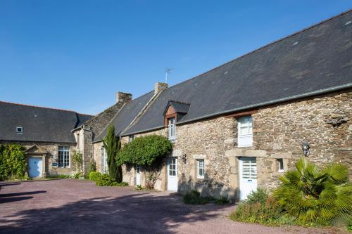an old stone house with a black roof at La Metairie-du-Vauhariot - Vue Mer et Mont Saint Michel - Piscine Chauffée - Accès GR34 in Cancale