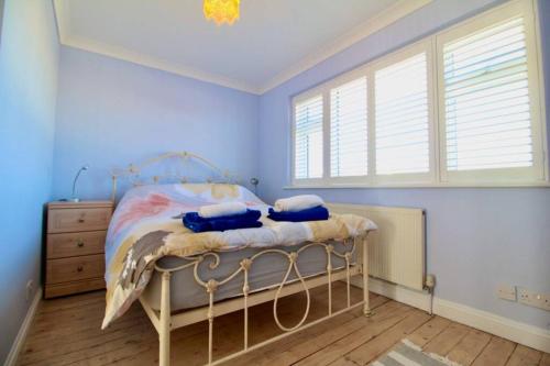 a bedroom with a bed with blue walls and a window at Serenity "your calm seafront retreat" By Air Premier in Seaford