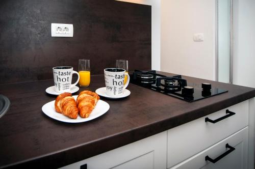 two cups of coffee and croissants on a kitchen counter at Deluxe Apartments A&A in Rovinj