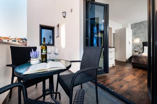 a dining room table with a bottle of wine and a book at Deluxe Apartments A&A in Rovinj