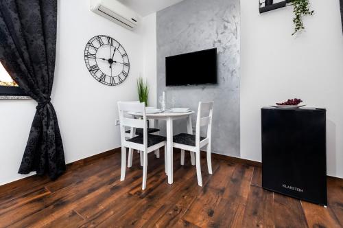 a dining room with a white table and chairs and a clock at Deluxe Apartments A&A in Rovinj
