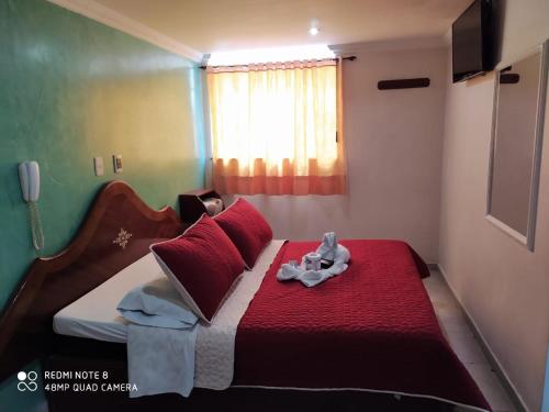un dormitorio con una cama roja y blanca con un animal de peluche. en Hospedaje Wicirare, en Bogotá