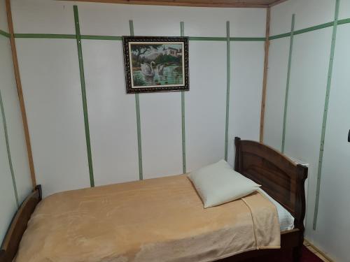 a small bed in a room with a picture on the wall at Sofra Kolonjare Agroturizem in Ersekë