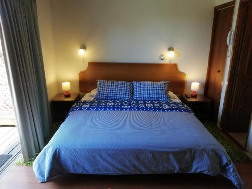 een slaapkamer met een bed met blauwe lakens en 2 lampen bij Hotel Rocas de Santo Domingo in Santo Domingo