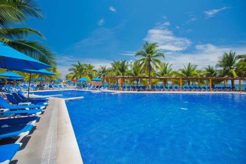 a pool at the resort with blue chairs and palm trees at Barceló Ixtapa - All Inclusive in Ixtapa