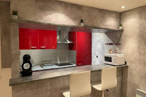 una cocina con armarios rojos y electrodomésticos blancos en Charmant Duplex, à 10 min de là frontière, Ornex en Ornex