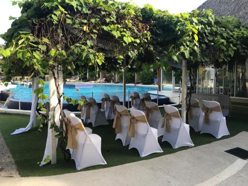 a group of tables and chairs in front of a pool at Seis Playas Hotel in Tamarindo