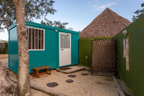 a blue and green tiny house with a tree at Xuux Peek by Tecnohotel in Yaxché