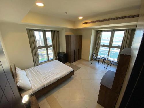 a bedroom with a bed and a table and windows at Beachfront Property With Atlantis The Palm & Skydive View In Dubai Marina in Dubai