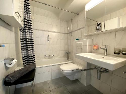 a bathroom with a sink and a toilet and a bath tub at zentrale TOP Wohnung Chesa Ravaisch in Davos