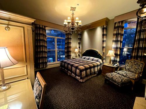 a bedroom with a bed and a chair and windows at Celebrity Boutique Hotel in Deadwood