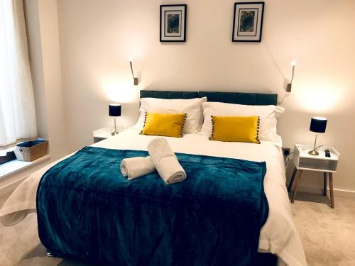 a bedroom with a large bed with two yellow pillows at Maplewood luxurious one-bed flat with free parking in St. Albans