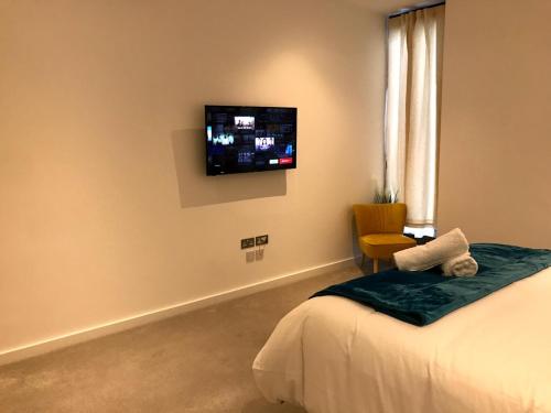 1 dormitorio con 1 cama y TV en la pared en Maplewood luxurious one-bed flat with free parking, en Saint Albans