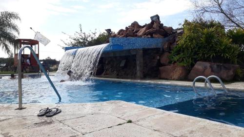 a pool with a water slide and a waterfall at SUEÑOS DE TERMAS in Chajarí