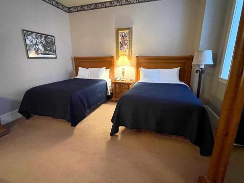 a hotel room with two beds and a lamp at Celebrity Boutique Hotel in Deadwood