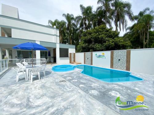 a pool with a table and chairs and an umbrella at Ecomarine Apart-hotel 800 m Beto Carrero in Penha