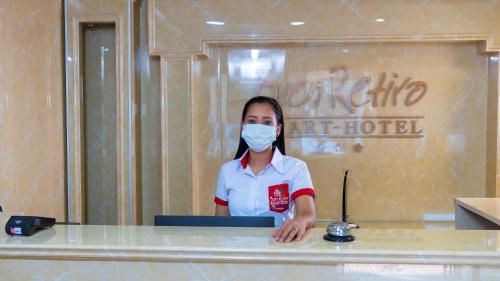 a woman wearing a mask at a counter in a hotel at Buen Retiro Apart Hotel in Santa Cruz de la Sierra