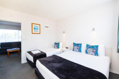 a hotel room with two beds and a couch at Chevron Motel in Taupo