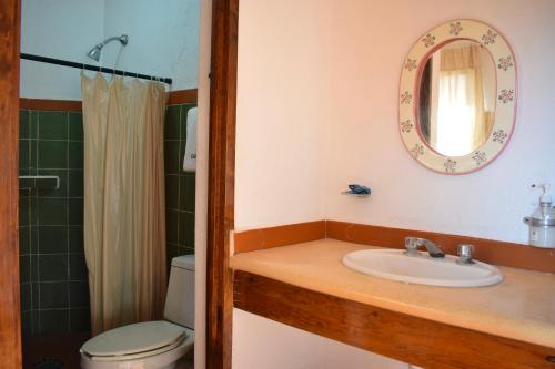 ein Badezimmer mit einem Waschbecken, einem WC und einem Spiegel in der Unterkunft Hotel Casa Arena in Zihuatanejo