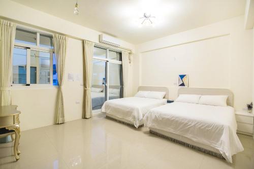two beds in a white bedroom with a window at Square B&B in Taitung City