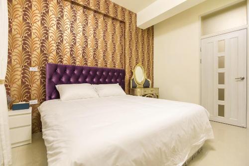 a bedroom with a large bed with a purple headboard at Square B&B in Taitung City