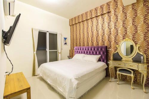 a bedroom with a bed with a purple headboard and a mirror at Square B&B in Taitung City