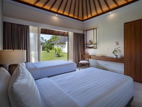 a bedroom with two white beds and a window at Villa Kailasha by Elite Havens in Tanah Lot