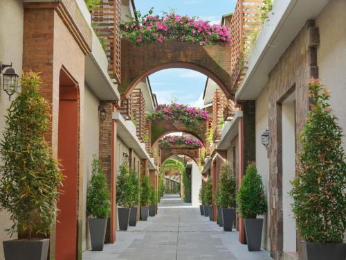 an alley with potted plants and an arch with flowers at Kayumas Seminyak Resort in Seminyak