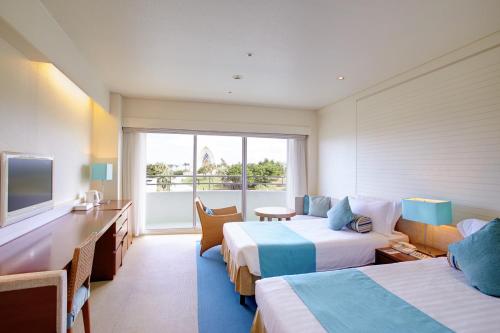 a hotel room with two beds and a desk at ANA InterContinental Manza Beach Resort by IHG in Onna