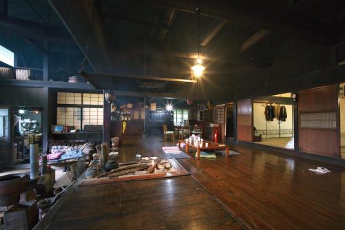 a large room with a wooden floor and a room with tables at Kamiya Rare Experience in a 180 Year Old Farmhouse Milky Way Irori Fire and Nature! in Iida