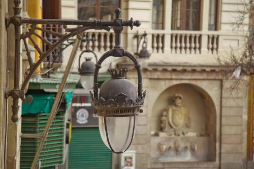 a street light with a statue in front of a building at Hostal Paris in Barcelona