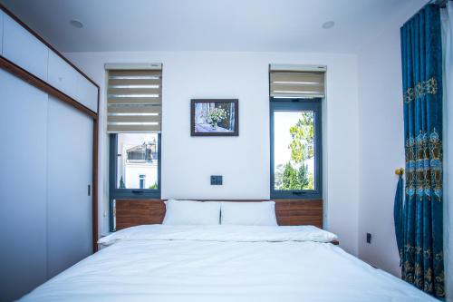 a bedroom with a white bed and two windows at Win Villa Coffee in Da Lat