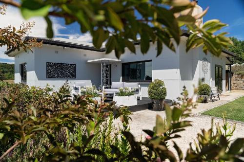 a white house with a patio and plants at Esto house in Crafers
