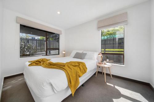 a white bedroom with a large bed and two windows at Kiwi style home! Views of lake. Large outdoor area in Queenstown