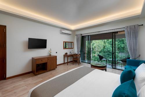 a bedroom with a large bed and a tv at Moksha at Kitulgala - Rainforest Boutique Hotel in Kitulgala