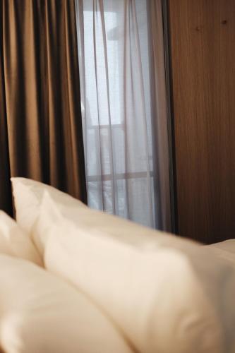 a bed with white pillows in front of a window at Belly Inn Douliu in Douliu