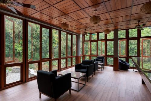 a room with chairs and a table and windows at Moksha at Kitulgala - Rainforest Boutique Hotel in Kitulgala