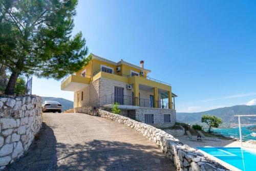 a yellow house on a hill with a swimming pool at marmar villas in Vlikhon