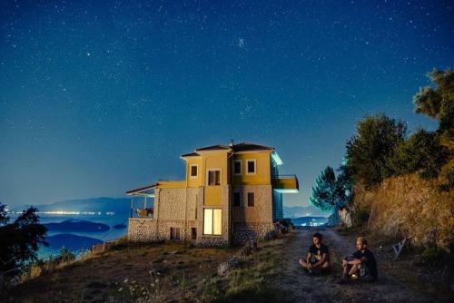 two people sitting in front of a house at night at marmar villas in Vlikhon
