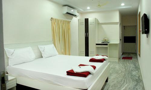 a bedroom with a white bed with red towels on it at Raya's Executive Homes in Kumbakonam