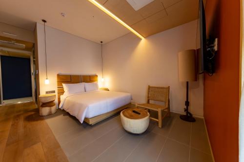 a bedroom with a bed and a chair and a television at Hound Hotel Haeundae Signature in Busan