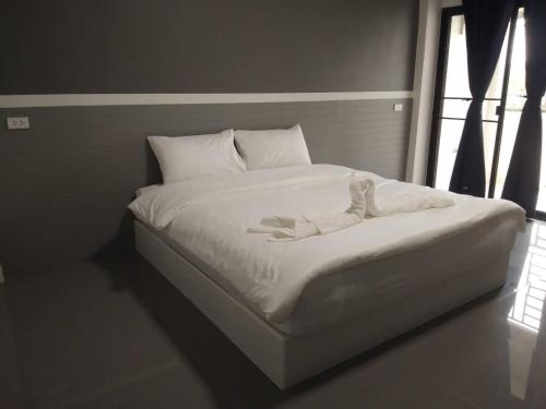 a white bed in a room with a window at ไนท์ ฟอร์ ยู เรสซิเดนซ์ in Buriram