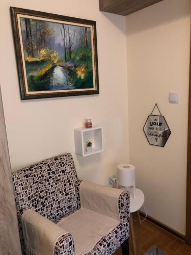 a living room with a chair and a painting on the wall at Sunčani Apartman in Brzeće
