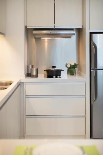 a kitchen with white cabinets and a pot on a stove at Citadines Uplands Kuching in Kuching