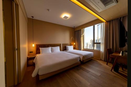 釜山にあるHound Hotel Haeundae Signatureのベッドと大きな窓が備わるホテルルームです。